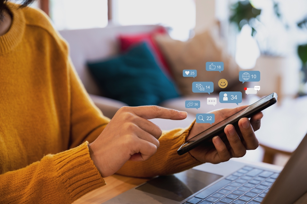 Hand of young woman using smartphone with notification icons, Social media concept.
