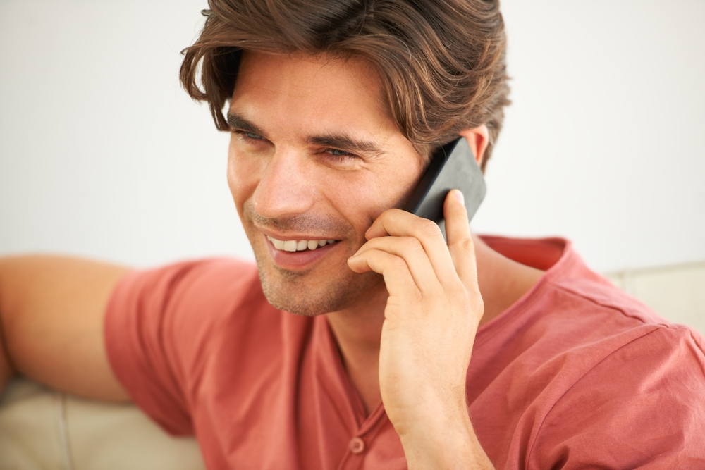 Man, smile and phone call to contact in home for social networking, mobile communication and cellphone in living room. Face, happy guy and and talking on smartphone for chat, conversation and hello