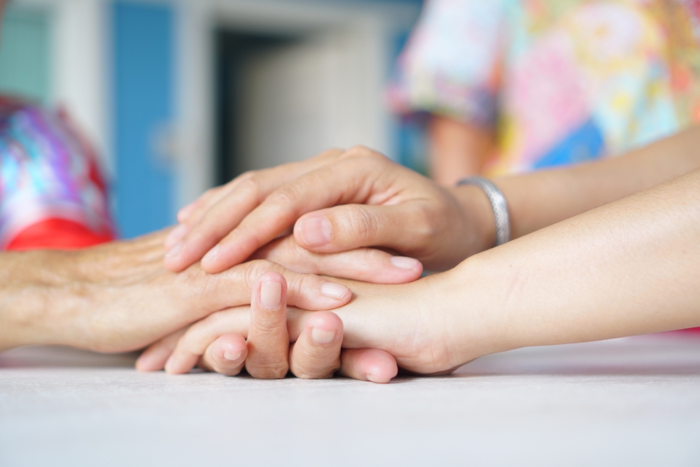 Asian woman is in the living room holding hands to encourage, sympathize, and comfort, taking care of a sick person at home.