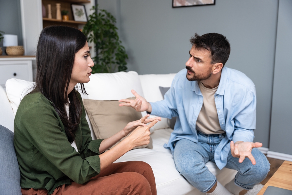 Young married couple husband and wife sitting at home having problems in their marriage and a cold relationship. A boyfriend and a girlfriend roommates have an argument about spending too much money