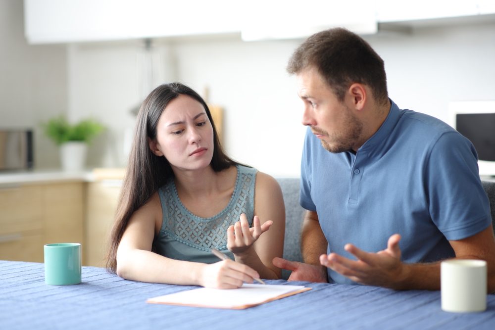 Angry woman asking for explanation to her confused partner in the kitchen at home