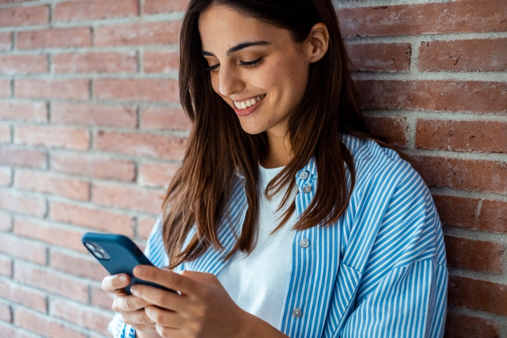 Young woman using smartphone at home – relaxed digital lifestyle, social media, chatting, messaging, dating and everyday technology in casual indoor setting