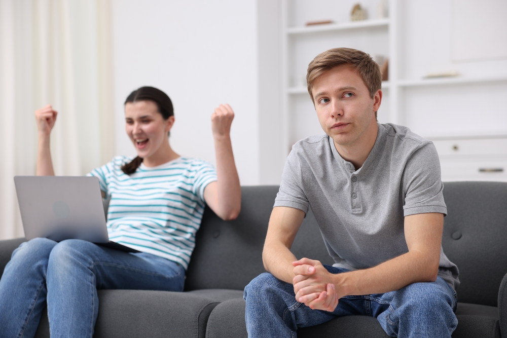 Man feeling jealous of woman's success at home, selective focus