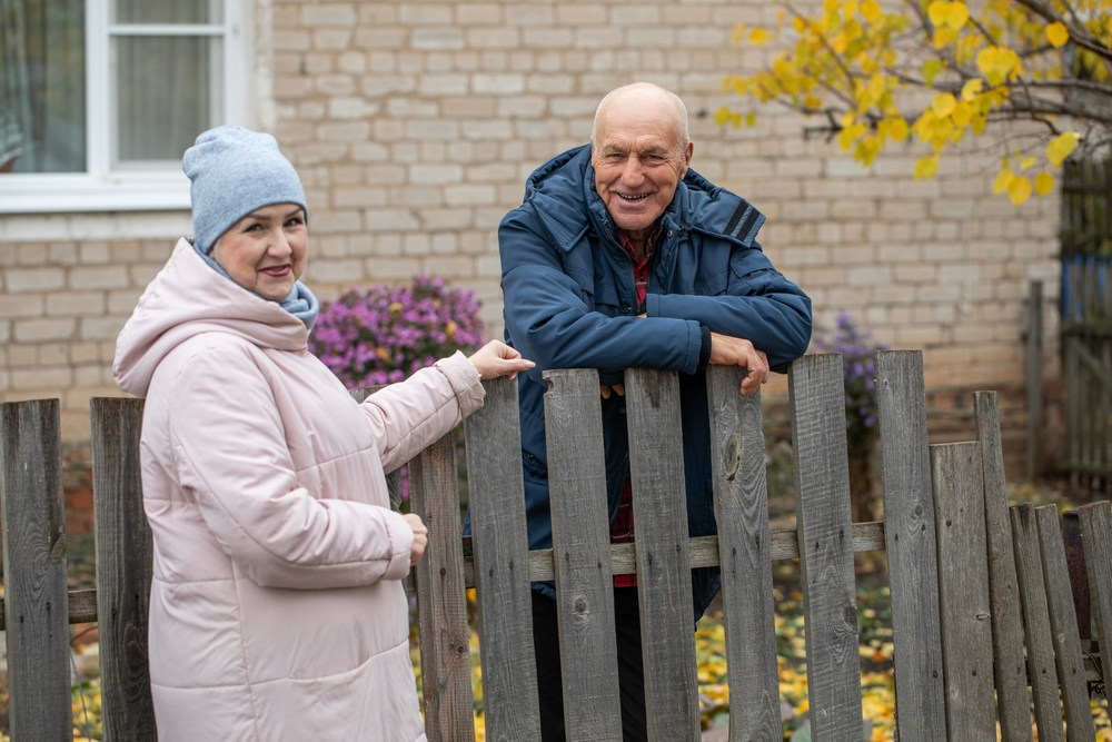 Summer cottage neighbors. An elderly couple near a wooden fence.