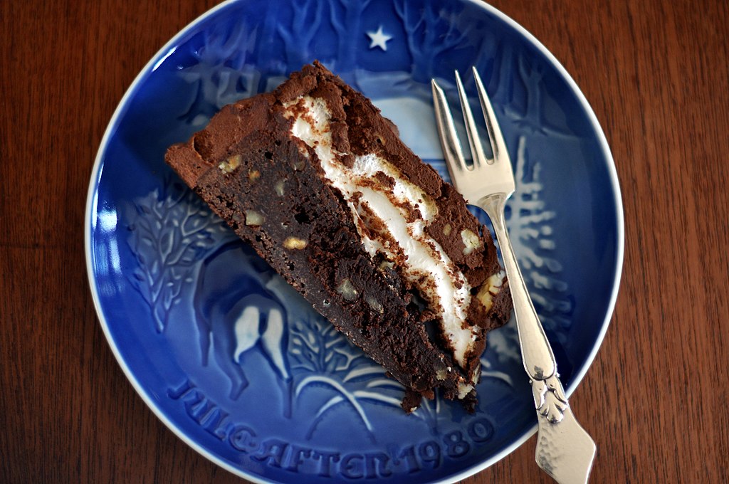 Slice of Mississippi mud pie with marshmallow swirl on a blue plate.