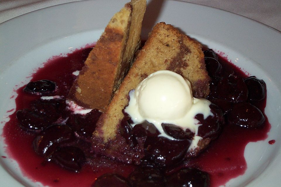 Pound cake slices with vanilla ice cream in a pool of cherry sauce.