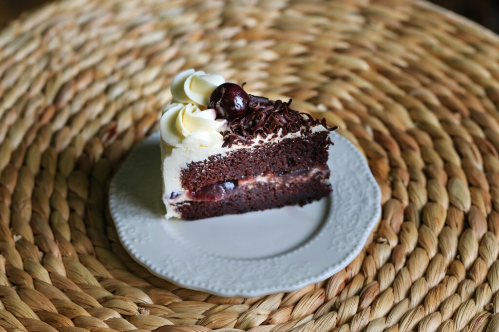 Slice of Black Forest cake with chocolate layers, cherry filling, and whipped cream.