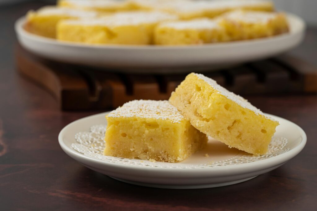 Lemon bars dusted with powdered sugar on a small plate.
