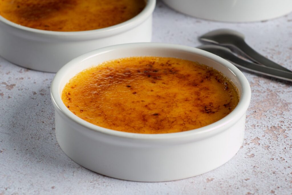 Crème brûlée with caramelized sugar top in white ramekins.