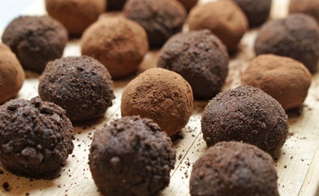 Chocolate truffles dusted with cocoa powder arranged on a wooden surface.