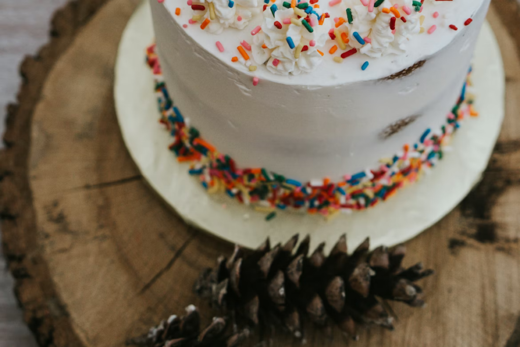 White frosted birthday cake decorated with rainbow sprinkles.