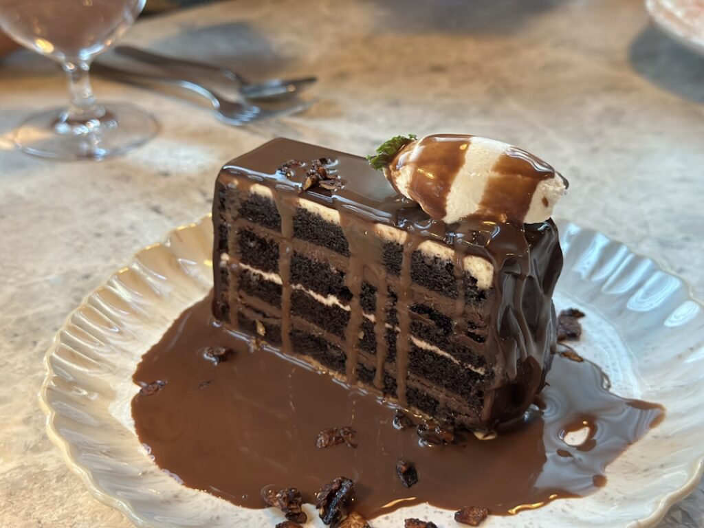 Tall slice of chocolate layer cake covered in chocolate ganache.