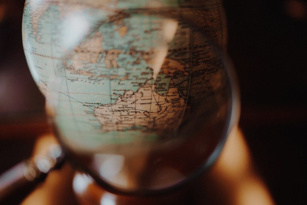 Close-up of a vintage globe showing the Americas, viewed through curved glass that distorts and magnifies the faded map details.
