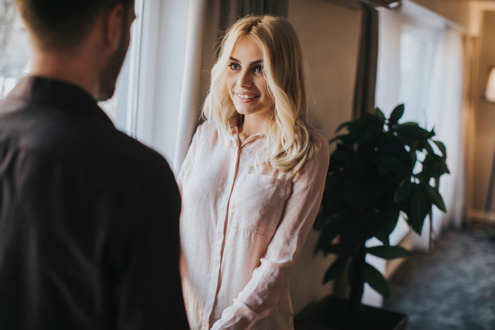 Lovely young couple standing by the window in the room