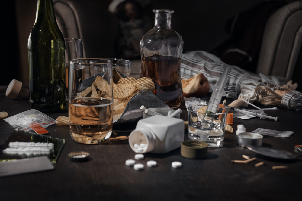 Various drugs, alcohol and cigarettes are on the wooden table. Substances that cause drug and alcohol dependence. Low key.