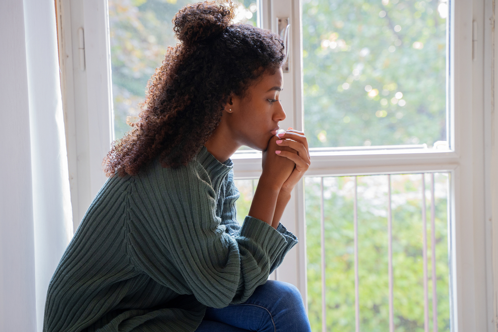 Young worried woman looking out of the window