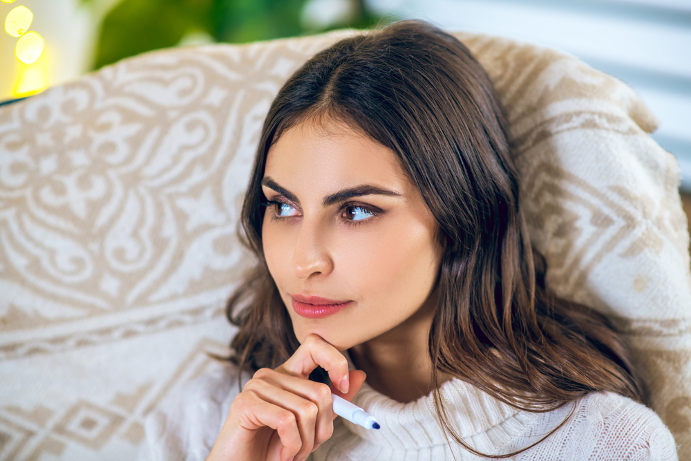 Wishlist. Woman looking thoughtful while making her wishlist