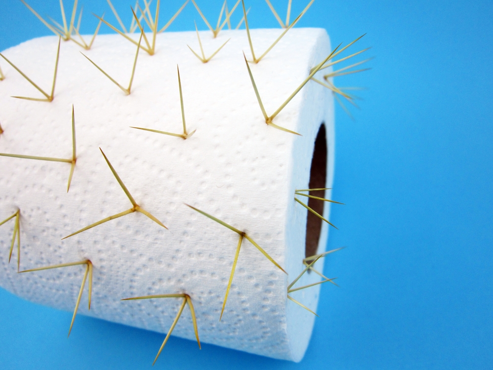 Toilet paper with thorns on colored background. Hemorrhoids concept                      