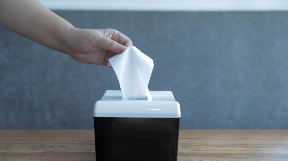 Someone pickup a tissue from a tissue box. A hand pick the tissue or holding a tissue.