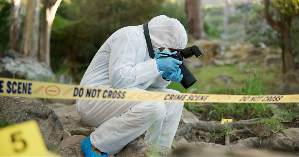 Forensic, photographer and police tape at crime scene for investigation in forest with evidence and safety hazmat..Csi quarantine, expert investigator and pictures for observation and case research