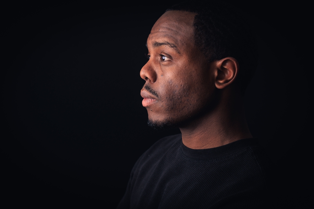 Thoughtful African American Man in Deep Contemplation Against Dark Background
