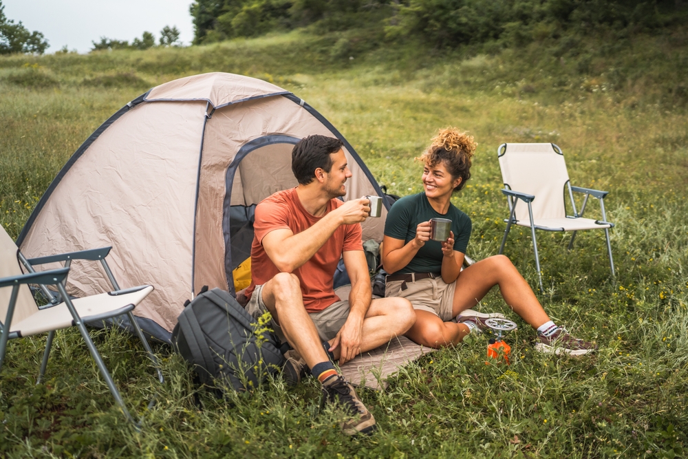 couple in love sit on the grass enjoy camp with coffee and talk