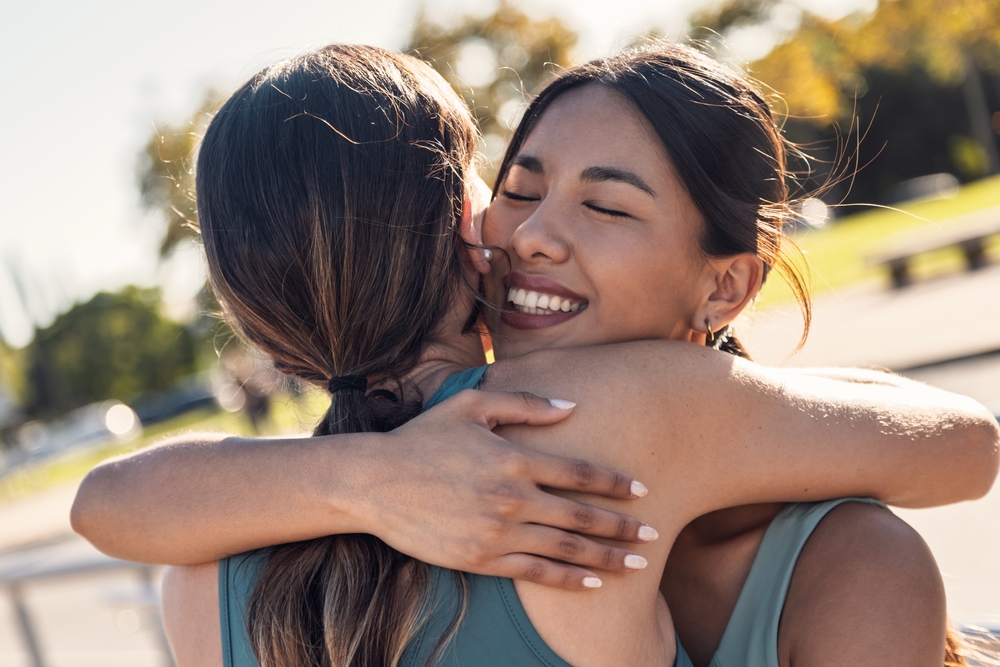 Shot of two sporty friends celebrating with a hug after going for a run around the city