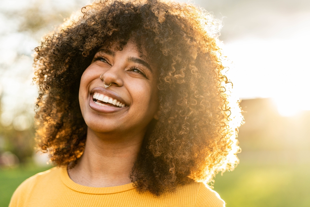 Happy young black woman smiling outside - Joyful beautiful girl laughing outdoors - Positive emotions, people portrait life style photo concept