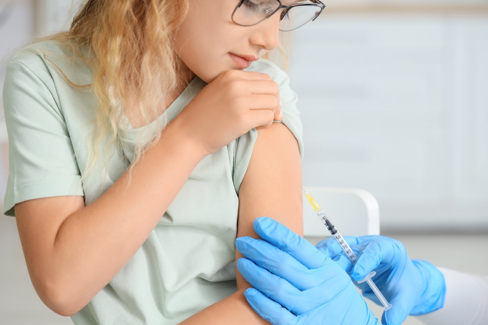 Little girl receiving vaccine from doctor in clinic, closeup