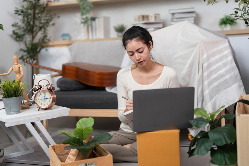 Moving and Remote Work. A young woman organizing her workspace at home while preparing for a move.