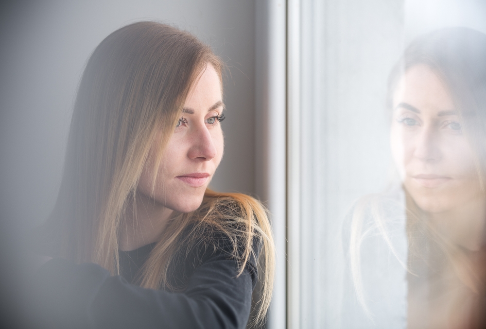 A serene female portrait in soft light, looking out with quiet contemplation and elegance.