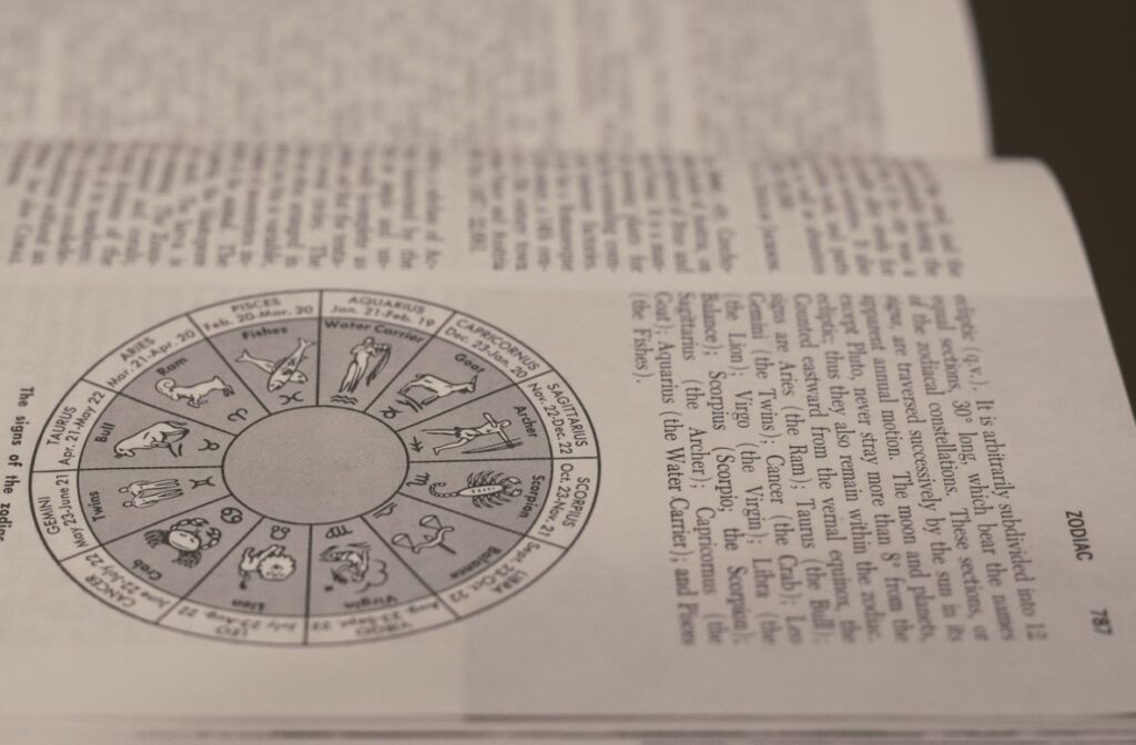 Open book showing a zodiac wheel diagram with all twelve astrological signs alongside text about astrology.