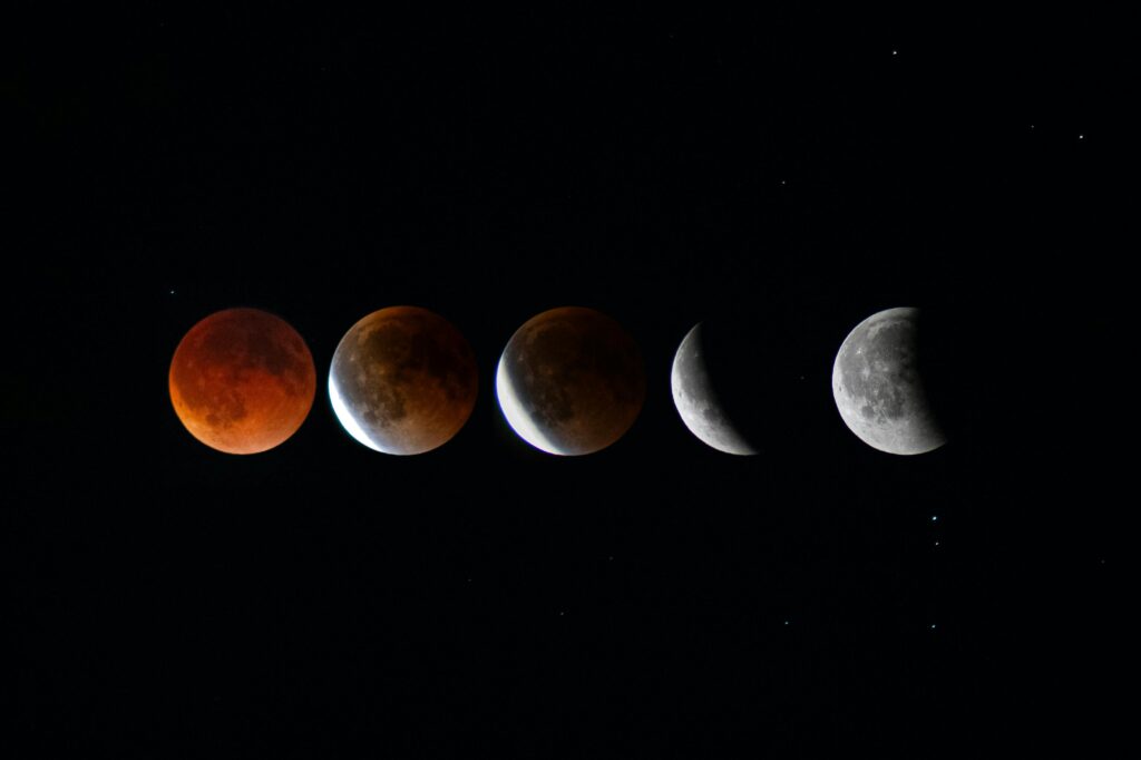 A composite photo showing five stages of a lunar eclipse arranged in a horizontal row from left to right, progressing from a fully red blood moon through partial shadow phases to a mostly bright, uneclipsed moon on the far right, all against a black background.