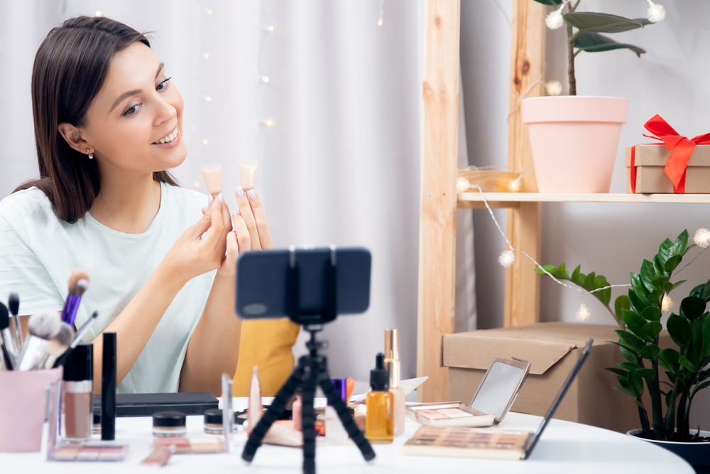 Beginner beauty blogger, young woman, makes review of foundation for skin, writes blog for subscribers on phone.