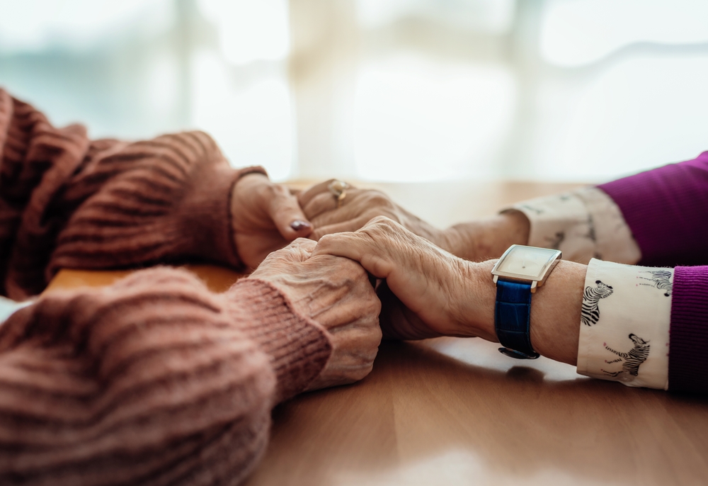 close-up detail of two elderly women holding hands. concept of care and affection in old age.