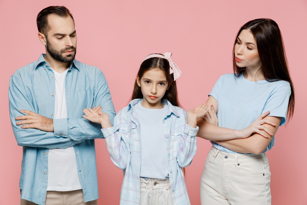 Young strict parents mom dad with child kid daughter teen girl in blue clothes spread hands like nothing to say isolated on plain pastel light pink background. Family day parenthood childhood concept