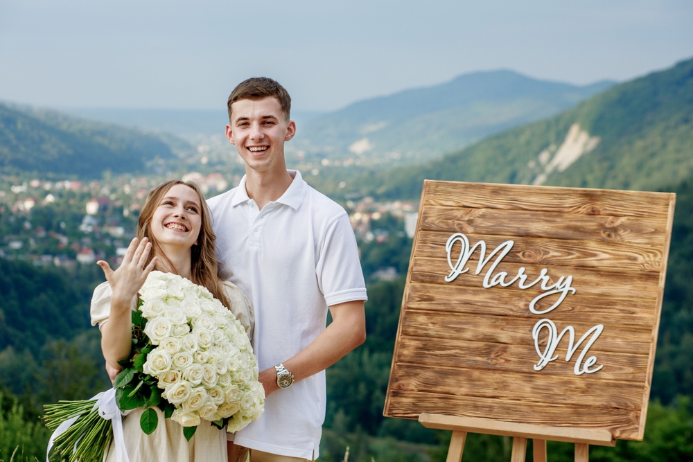 Happy young couple after making a proposal against the background of a mountain landscape. She said yes. An offer of a hand and a heart.