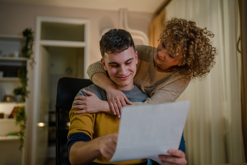 mature woman and son caucasian man teenager receive letter read good news student get scholarship or invitational letter from university share good news and excitement with his mother real people