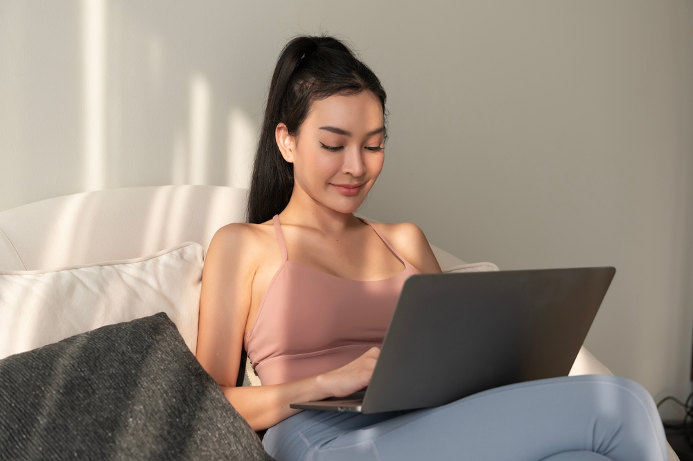 Young asian woman working with laptop in living room at home