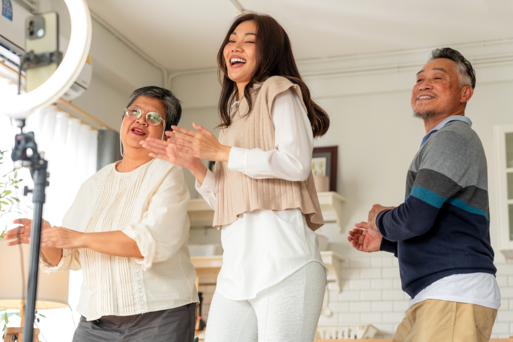 family streaming lives reel funny dance with daughter teen in living room home background by smartphone gadget sharing experience lives video on social media application broadcast family technology 