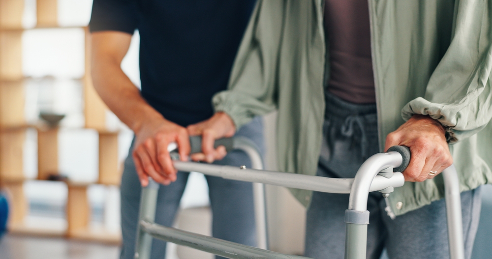 Physical therapy, senior patient and help with walker for support, injury or arthritis. People, therapist and healthcare with walking frame, rehabilitation and recovery of muscle in osteoporosis