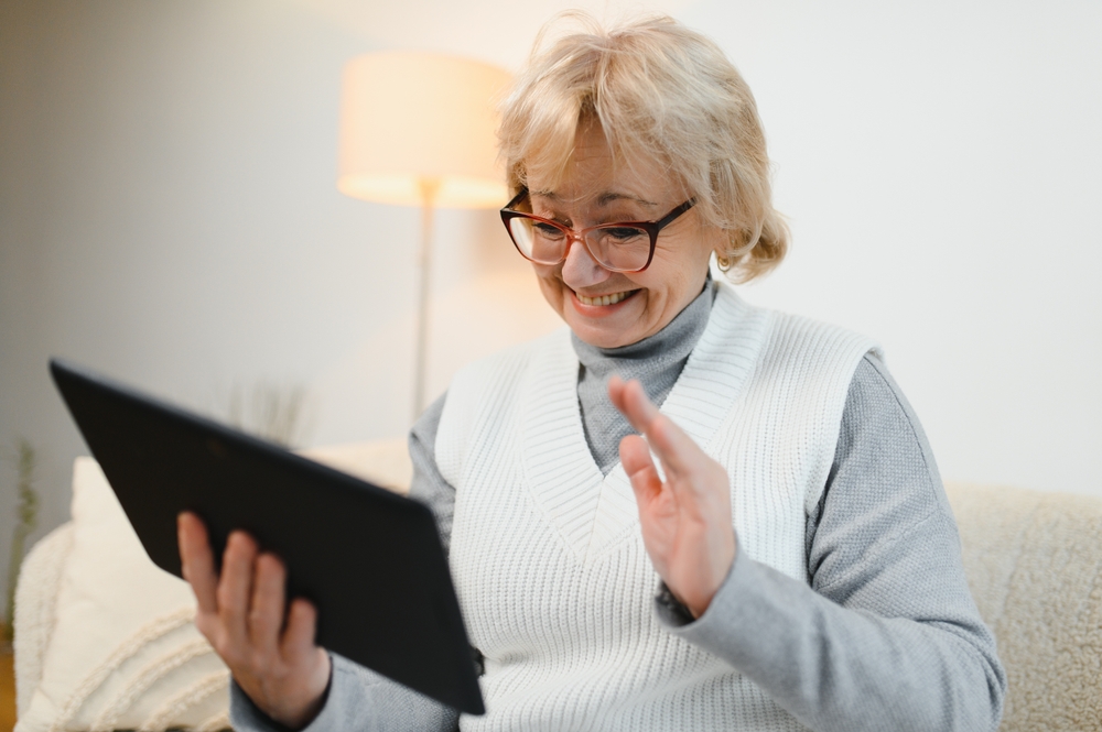 Old happy woman having a video call with her family on a tablet.
