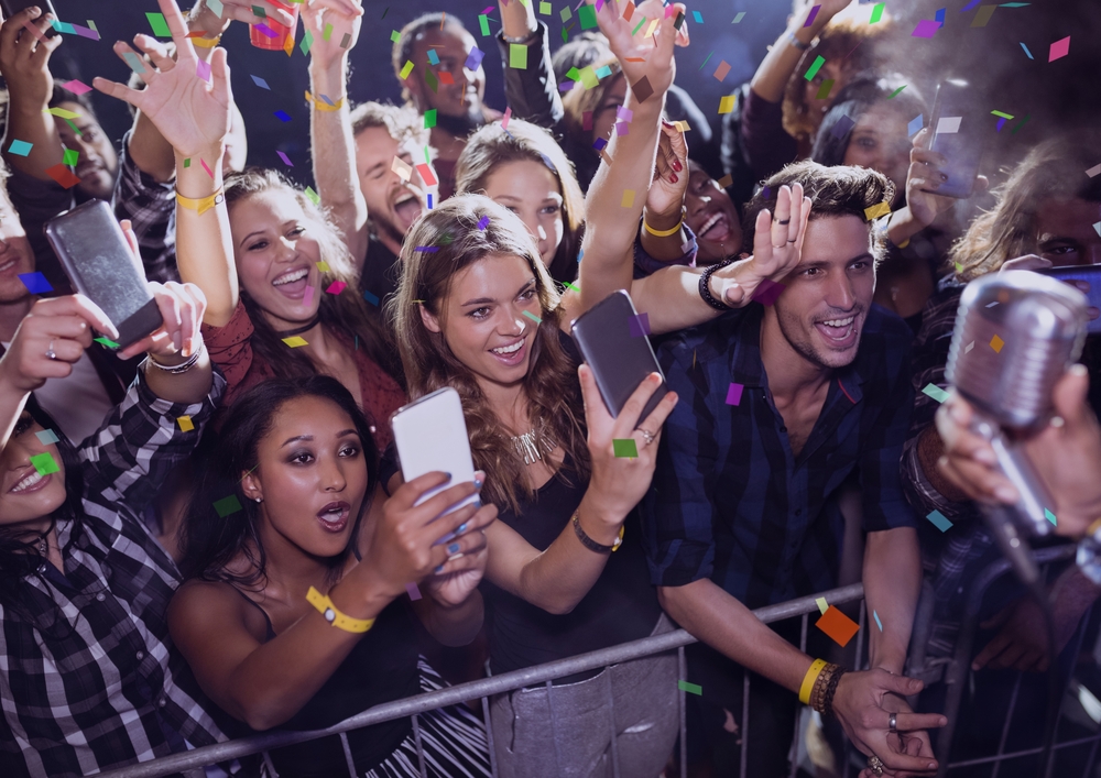 Digital composite of People having fun and making photos at a concert with 3D confetti
