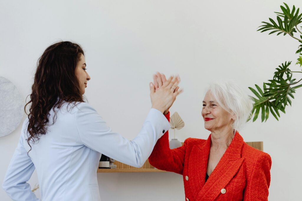 Woman in Blue Blazer Doing a High Five with Woman in Red Blazer
