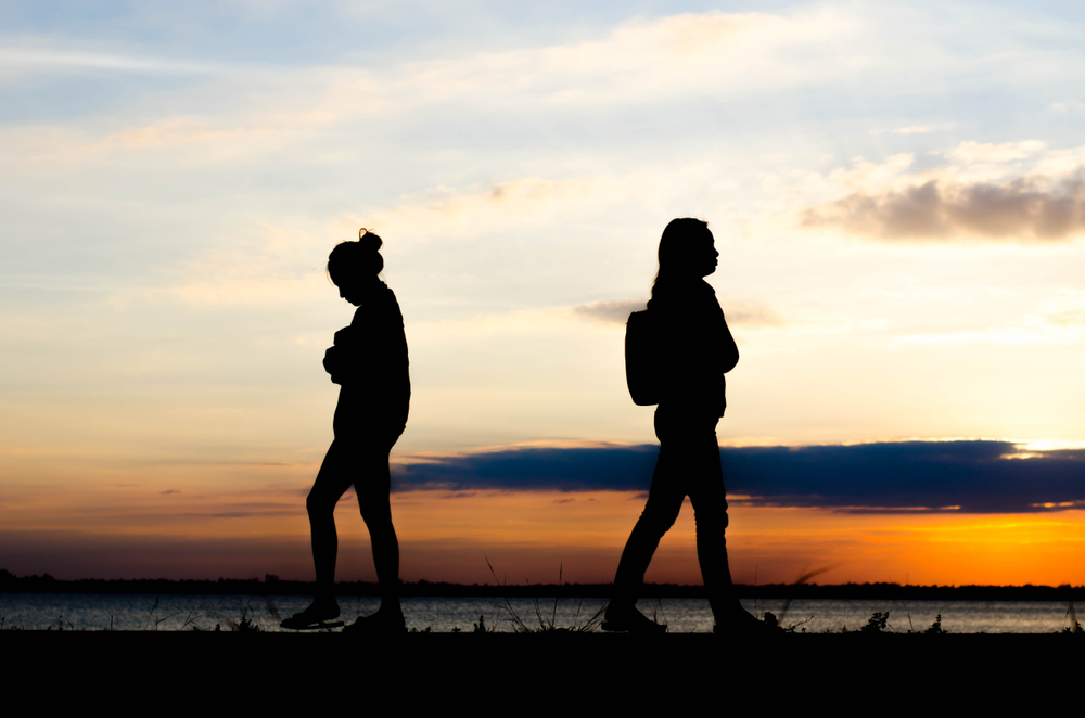 Couple woman silhouette standing sad  during sunset and beautiful sky.