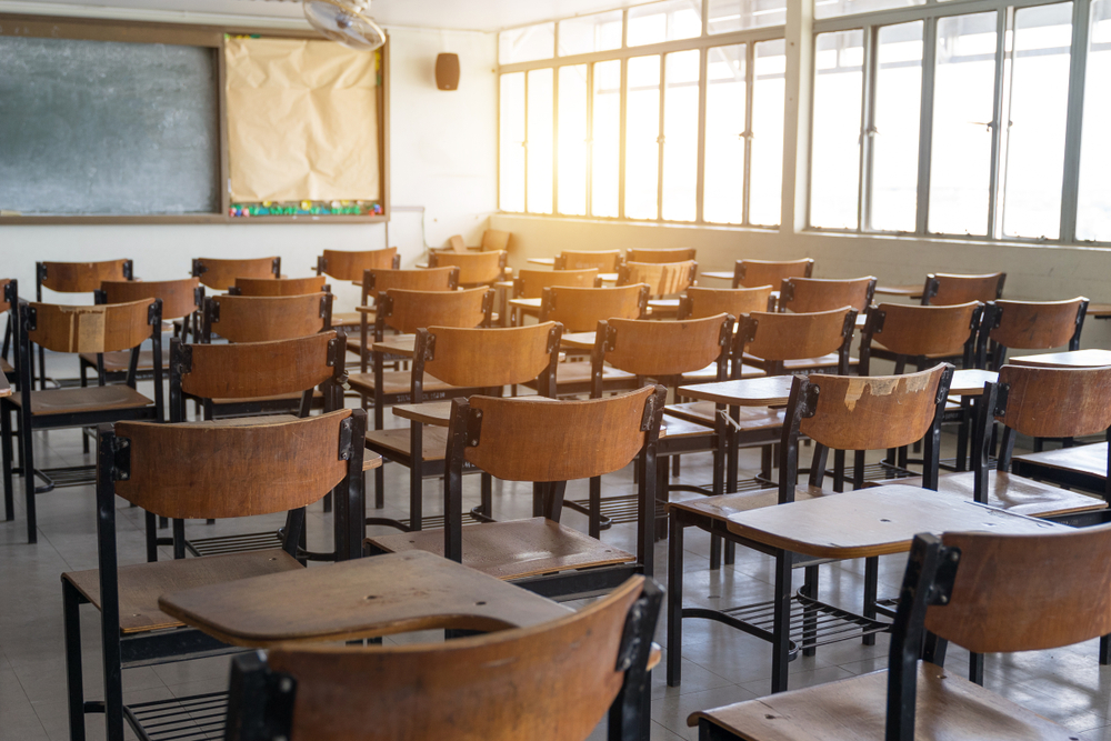 Empty classroom with a lot of chair with no student. Empty classroom with vintage tone wooden chairs. Back to school concept.