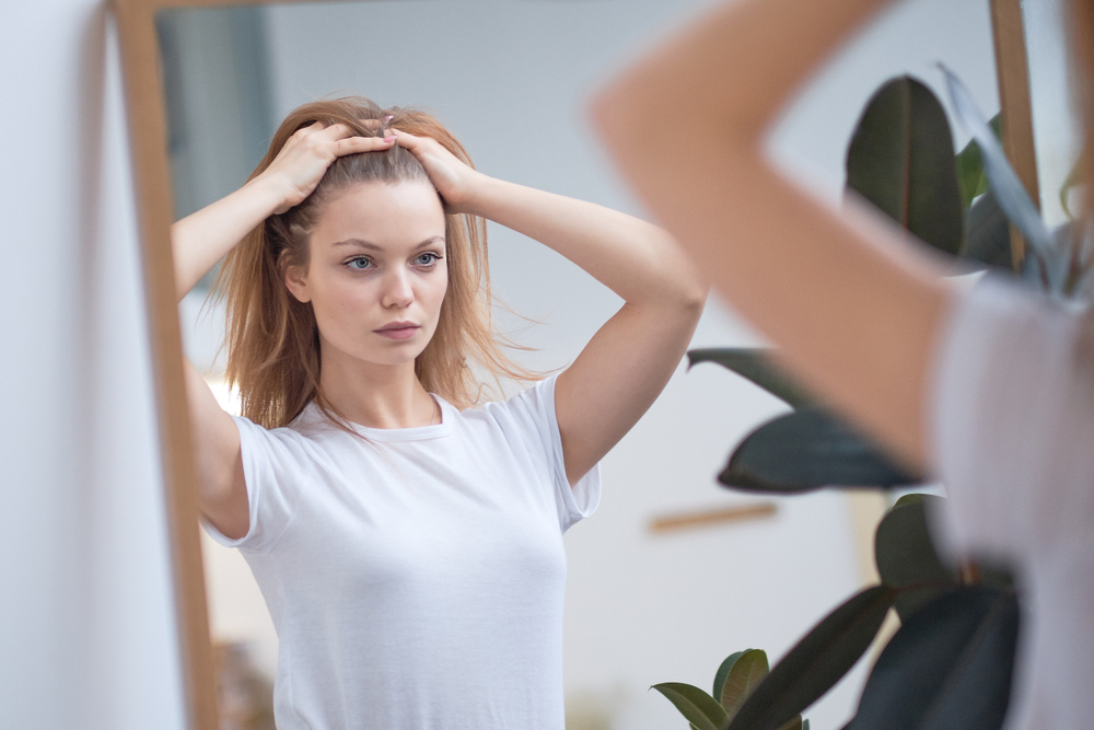 beautiful young woman looks at her reflection in the mirror. dissatisfaction with appearance, the desire to have plastic surgery, the search for flaws in himself.