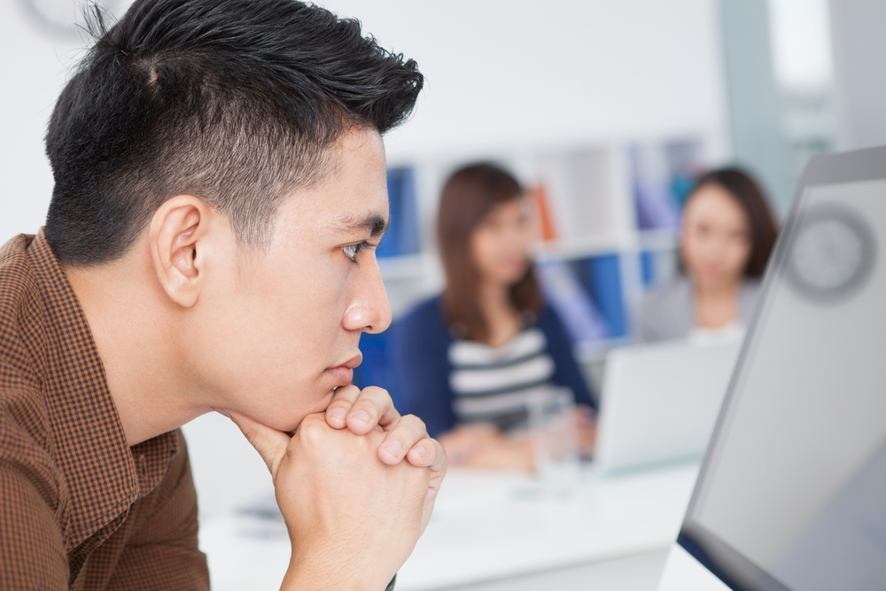 Profile view of a serious businessman looking at the monitor on the foreground