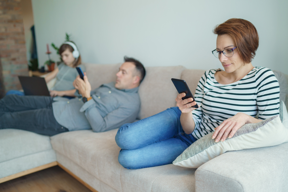 Technology addicted family: parents and child use laptop and mobile phones. Mom, dad with daughter obsessed with devices overuse social media, internet addiction concept