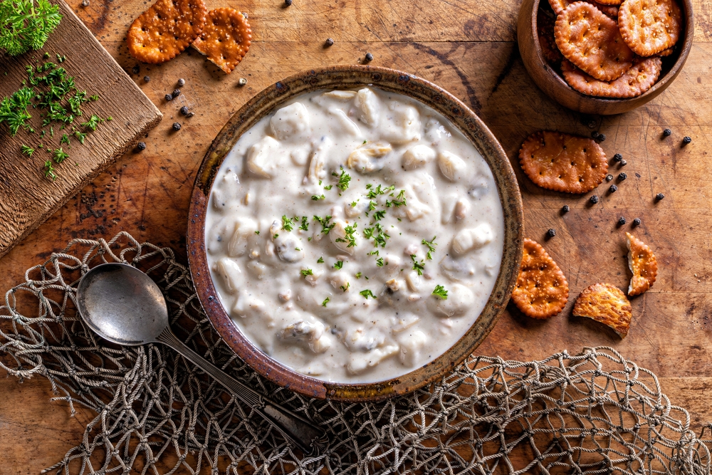 A bowl of delicious homemade New England clam chowder with parsley garnish and salted crackers